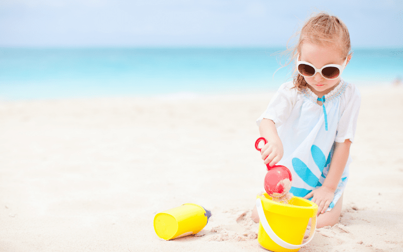 little girl playing with a bucket and shovel at the beach