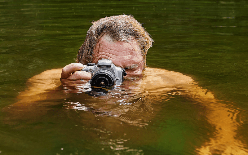 man in the water pointing a waterproof camera at the viewer