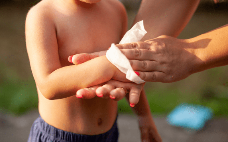 woman wiping a child's hand with wet wipe