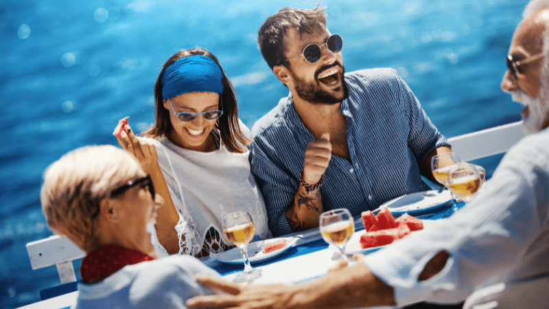 friends enjoying wine and food on a boat. ocean in background