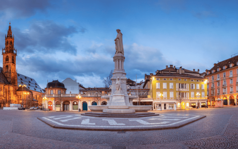 Statue in a square surrounded by beautiful buildings in Bolzano, one of the best places to visit in the Dolomites