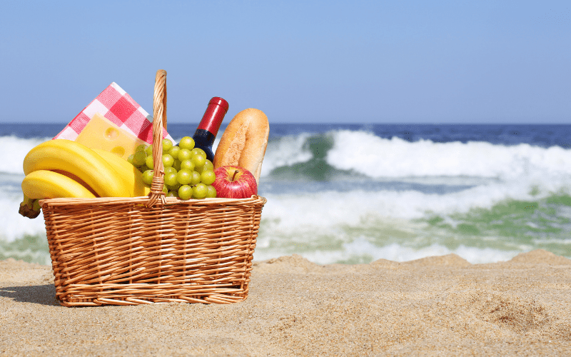 basket full of fruit, wine and bread at the beach