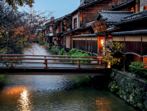 River running through Kyoto at twilight. Bridge and houses in foreground.