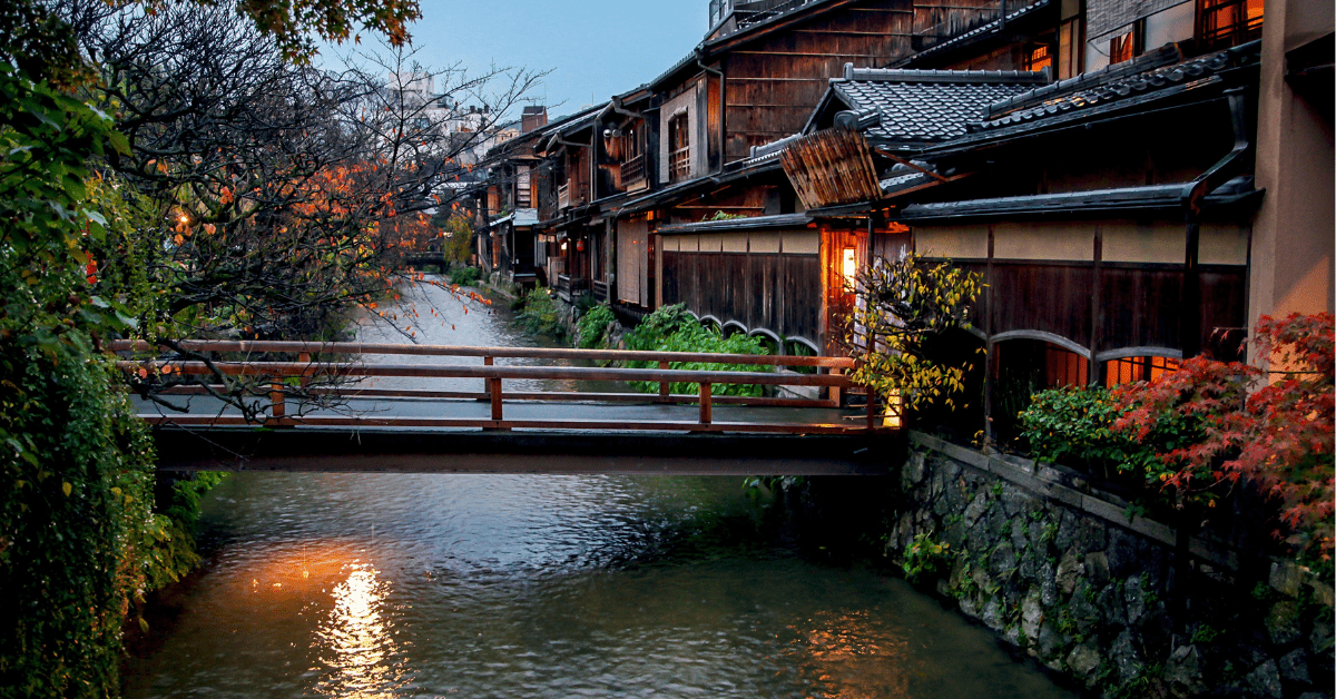 River running through Kyoto at twilight. Bridge and houses in foreground.