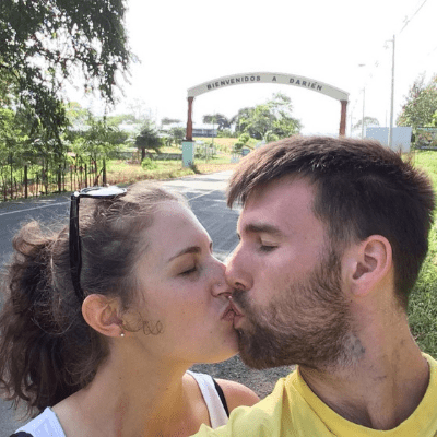 Erie Conners, author of "Driving in Panama" guest post, kissing her husband in front of the "Welcome to Darien" road sign