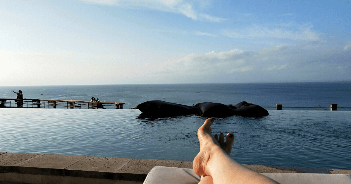 luxury experiences in Bali - feet on a lounge chair with pool in background
