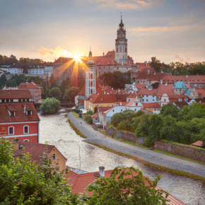 Sun setting behind Cesky Krumlov. River in foreground, castle in background. Text overlay says "Czech Republic 10 most beautiful spots"