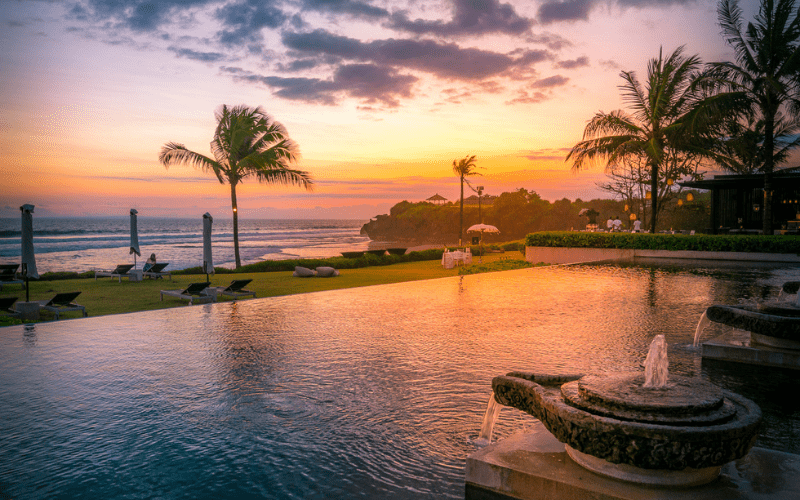 Sunset over the ocean, behind a pool at Soori Bali luxury hotel