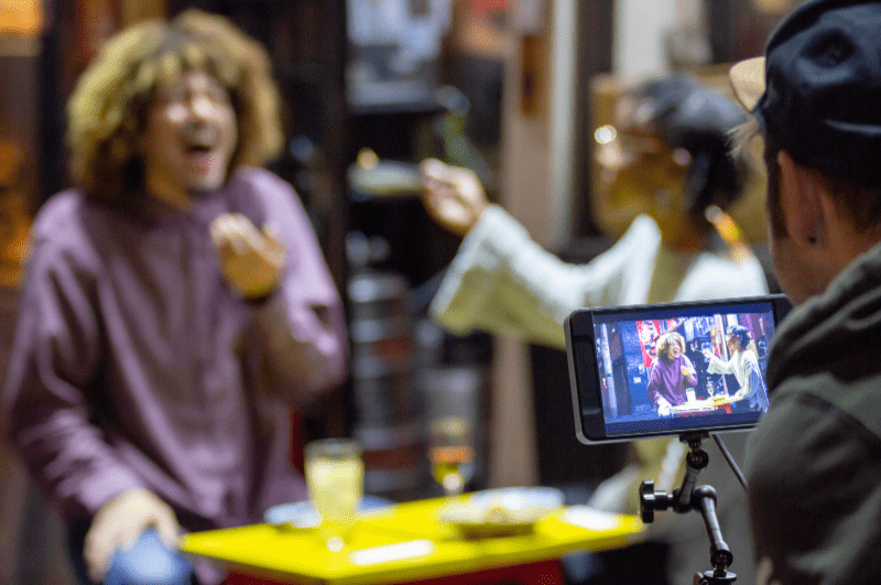 person videoing two people at a table