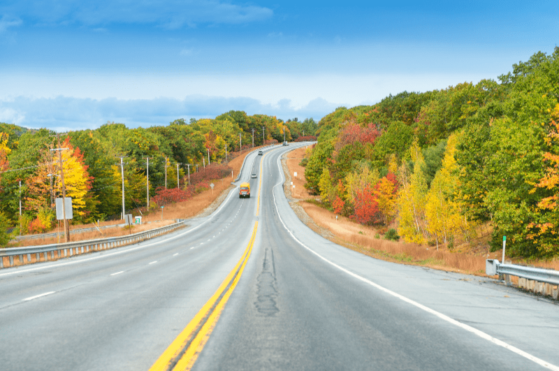 Leaf peeping is one of the best things to do in New England in early October. Here's a road lined with fall colors. The entire area is blanketed with reds, oranges, and yellows, whether you're doing a mountain or coastal New England road trip. So pick your favorite.