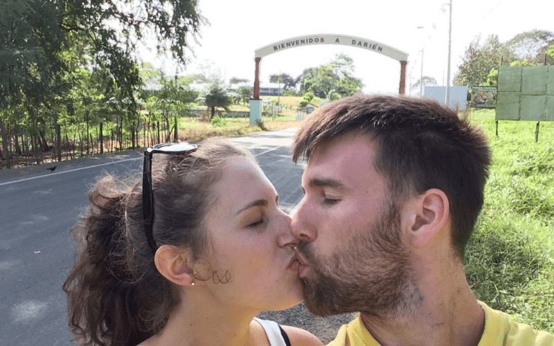 Author with her husband kissing in front of the Bienvenidos a Darien sign