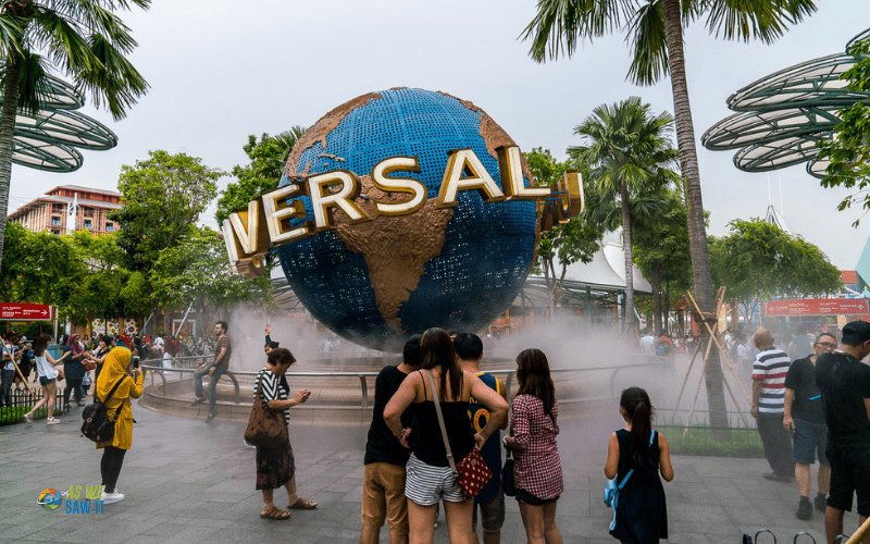 People walking around in front of the Singapore Universal Studios globe