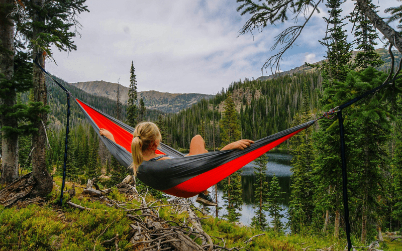 How to slow travel - a woman relaxing in a hammock and looking at the scenery