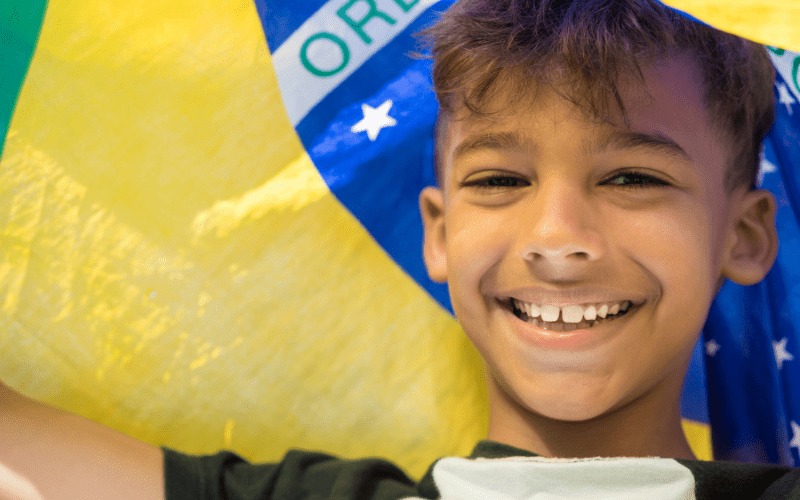 smiling boy with Brazilian flag behind him