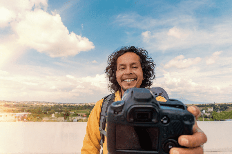 A man pointing a DSLR camera at himself. That's certainly one way to make videos while traveling!