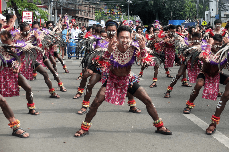 men parforming in the street at a Dinagyang festival parade