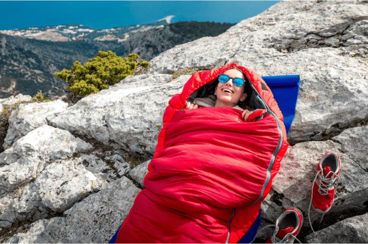 person in a sleeping bag on a rocky surface