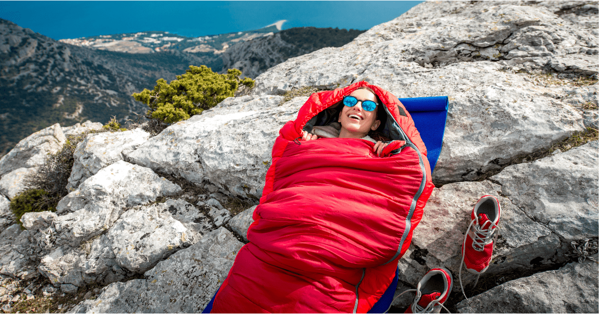 person in a sleeping bag on a rocky surface