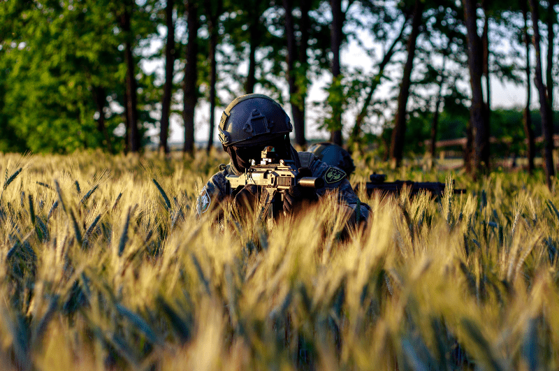 Person hiding in the grass with an Airsoft rifle