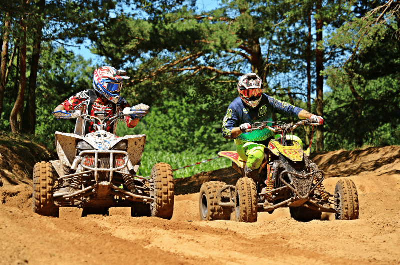 two people riding on atv vehicles