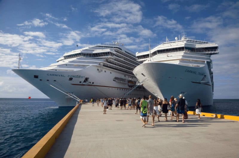 Passengers walking toward ships offering cheap Cozumel cruises in San Miguel de Cozumel Mexico.