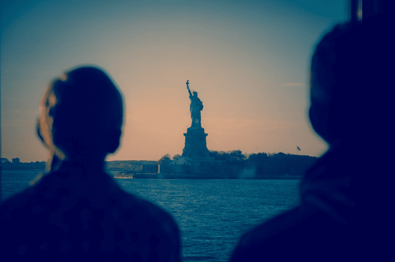 Silhouette of two people on the Staten Island Ferry looking at the Statue of Liberty