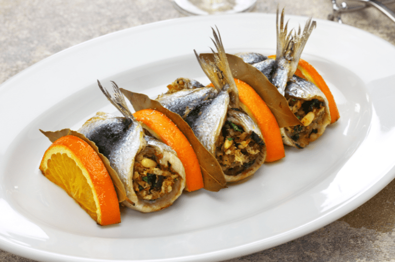 three rolls of sarde a beccafico separated by orange slices