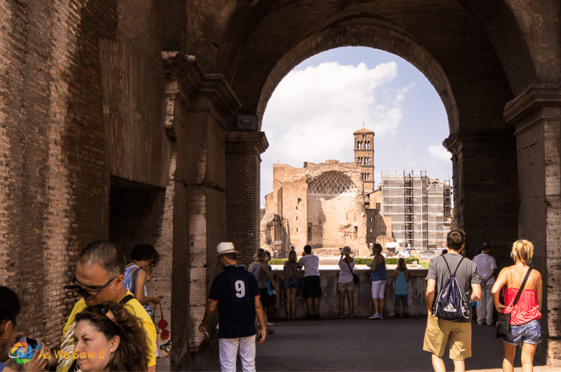 People walking through a passageway at the Colosseum in Rome. Roman forum in background