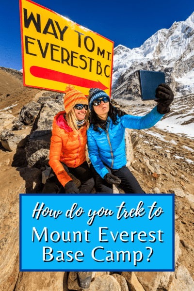 Two women in front of a Sign pointing the way to Mt Everest Base Camp. Text overlay says "How do you trek to Everest Base Camp?"