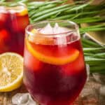 two glasses of tinto de verano wine cocktail over ice, with a sliced lemon on the side