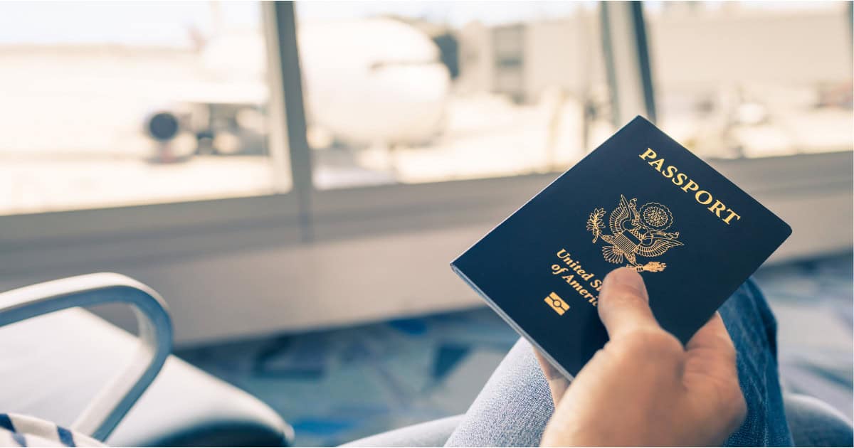 hand holiing a US passport in an airport seat