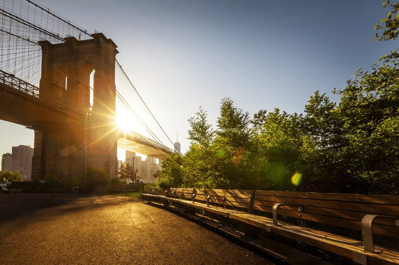 Sun setting behind one of the pylons, as seen from Brooklyn Bridge Park, best parks in new york city, parks in nyc