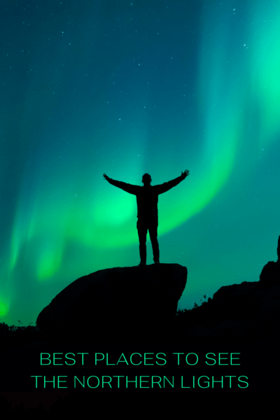 A silhouette of a person in front of the Aurora Borealis