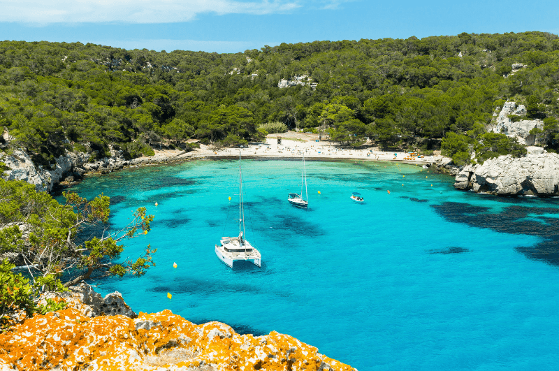 Beach in Menorca, clear water and boat.