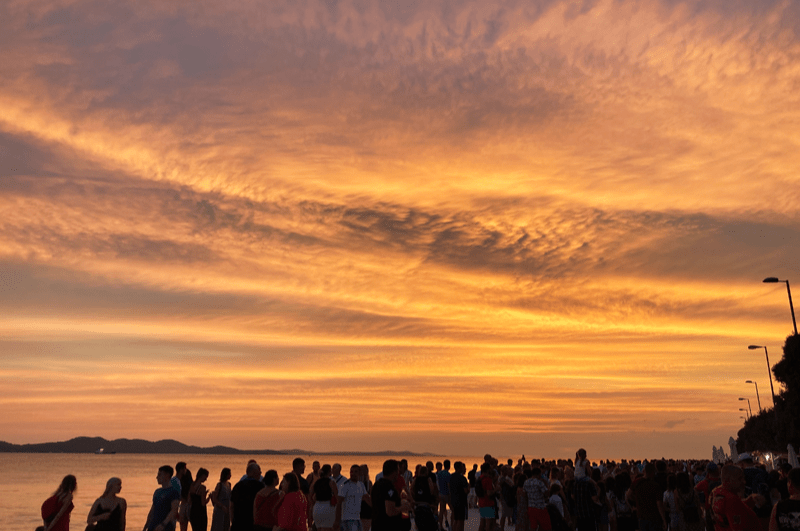 People watching the sunset over the water in Zadar, Croatia,