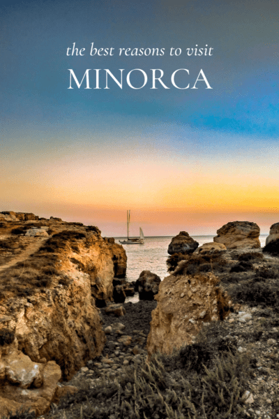 Rocks framing a boat, sunset in Menorca. Text overlay says "the best reasons to visit menorca"