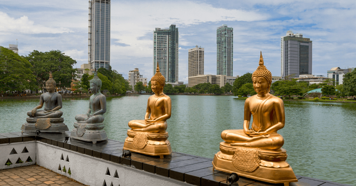 Buddha statues along the water in Colombo Sri Lanka, with skyscrapers in the background