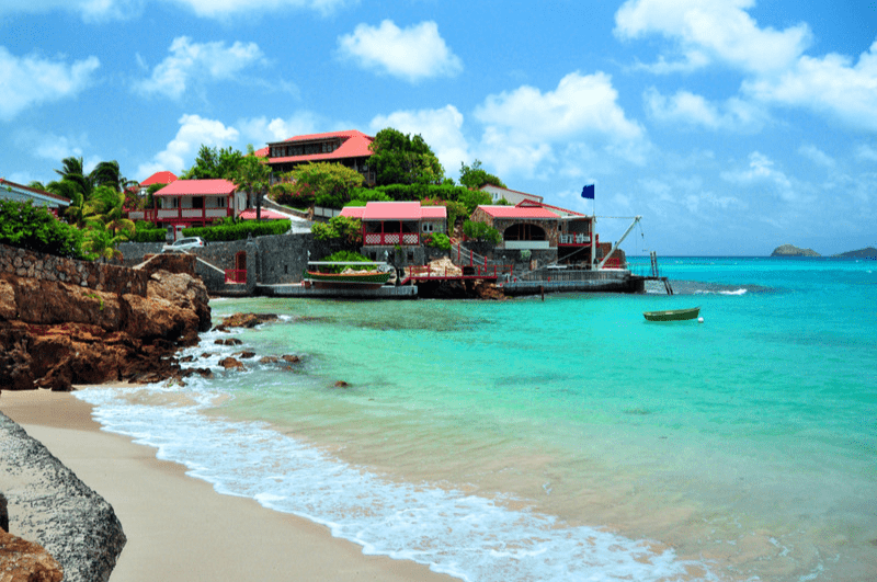 Luxury home on a rocky hill overlooking the Caribbean. Beach in foreground.