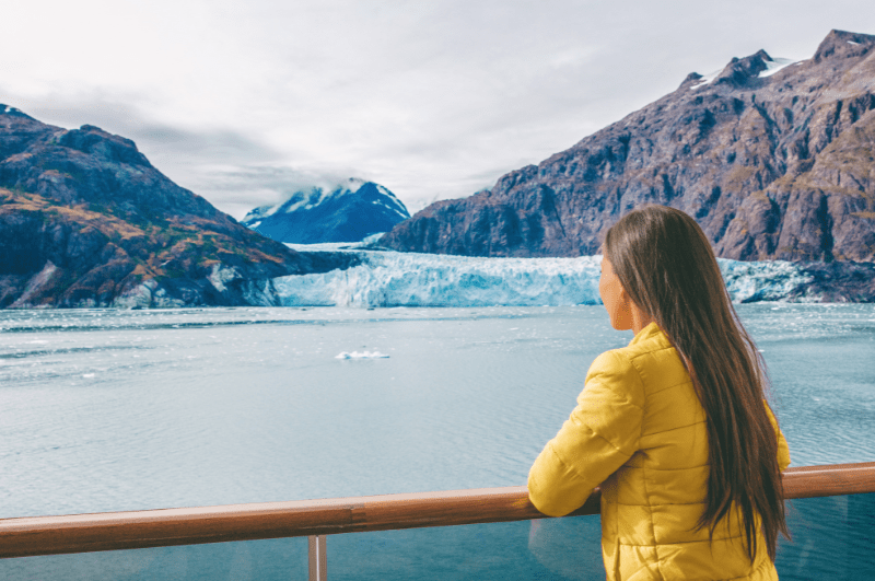 Woman on an Alaska cruise ship looking at an iceberg