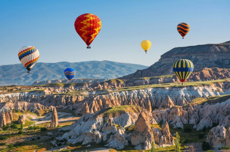 Hot air balloons over fairy chimneys in Cappadocia. This is one of the best places to visit in Turkey for tourists.