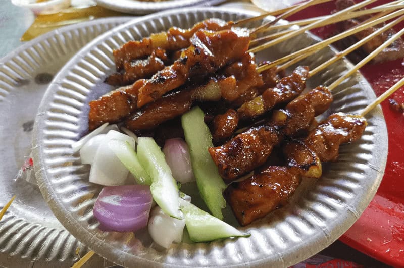 BBQ satay skewers with vegetables on a plate. One of the top budget Singapore dishes.