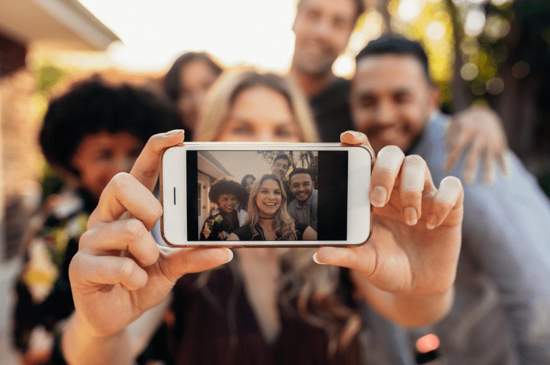 A group of people taking a selfie photograph with a phone