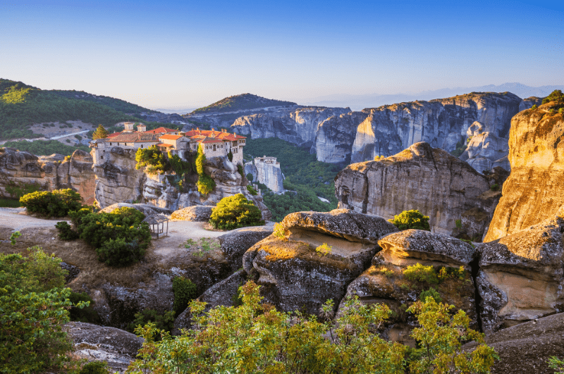 Monastery of the Holy Trinity, atop a rock in Meteora, Greece. Surrounded by trees.