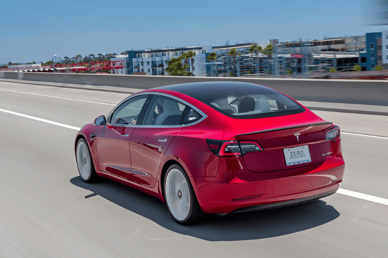 Rear view of a red Tesla model 3. Eco-friendly best car for European road trip adventures.
