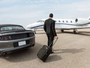 Man leaving his car and approaching a private jet with a carry-on suitcase. Private jet etiquette says you should pack light.