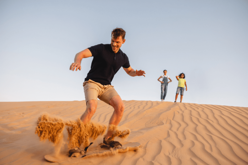 Man sandboarding in the desert in Dubai UAE