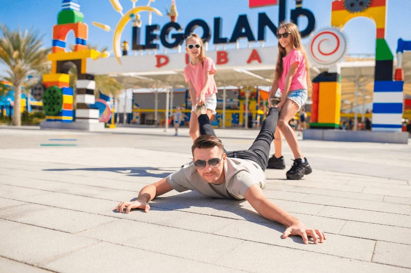 Man being dragged by two girls in front of Legoland