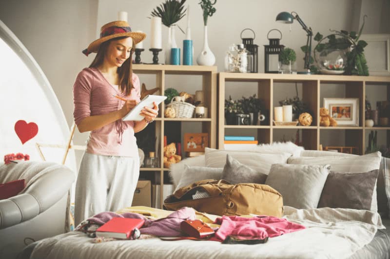 Woman making a checklist of what to pack for a city break.