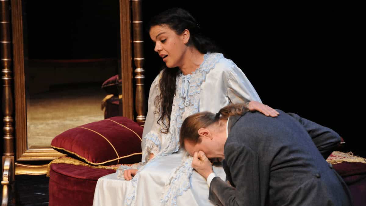 Woman singing while a man has is head on her lap