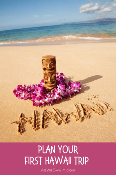 Tiki and lei on a beach, with the word Hawaii carved into the sand. Text overlay says "Plan Your First Hawaii Trip" As we saw it dot com